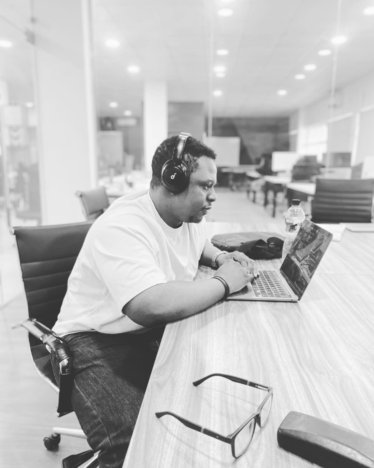 Ademola at work, headphones on, at his laptop